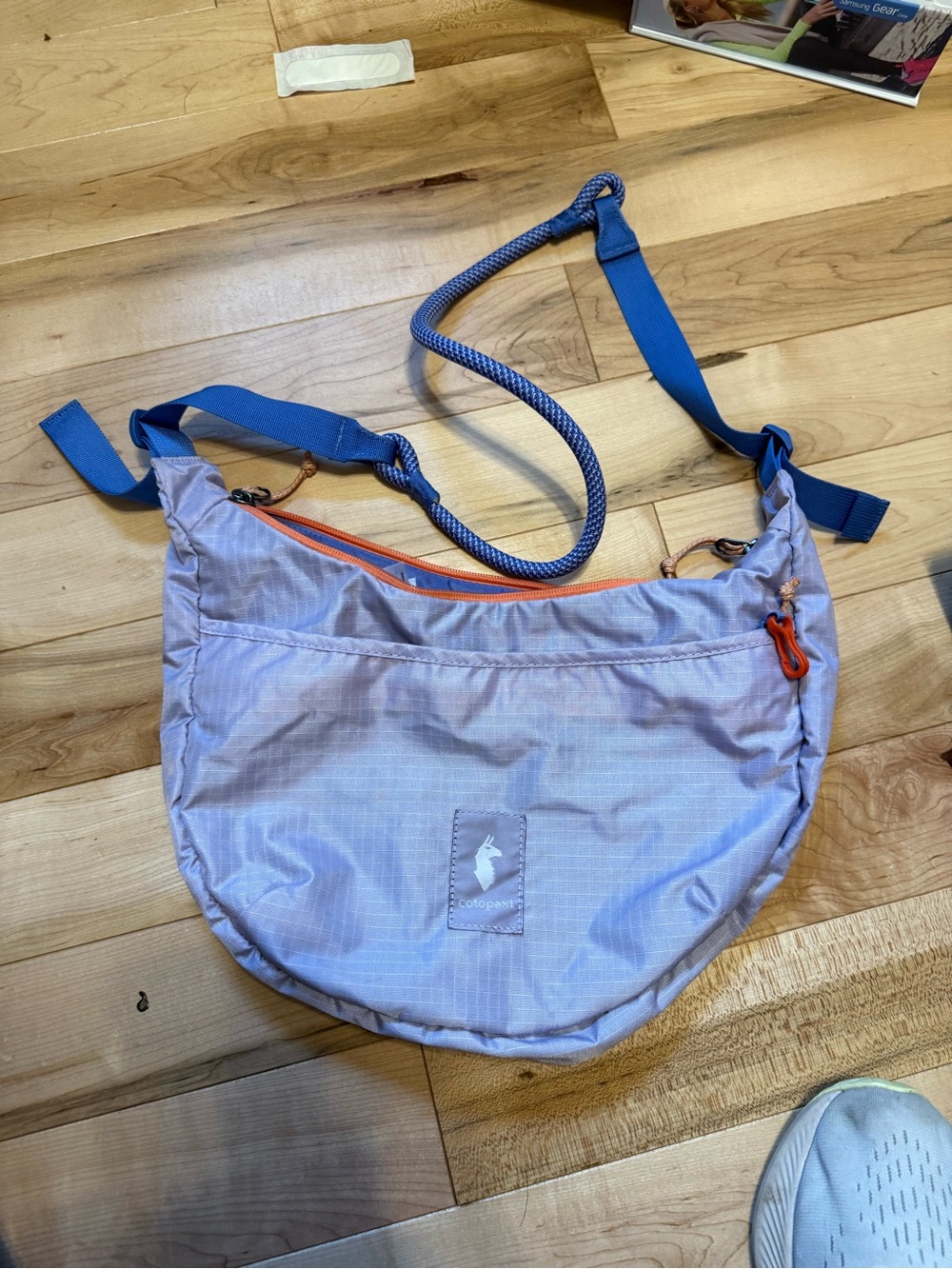 cotopaxi Lavender Crossbody Bag with Blue Strap and Orange Zipper Accents